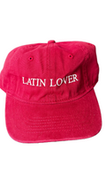 A red baseball cap with 'Latin Lover' embroidered in white script across the front.